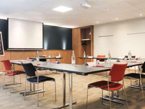 a conference room with tables and chairs and a screen at ibis Lyon Centre Perrache in Lyon