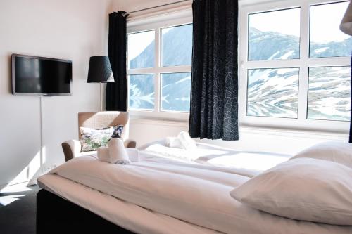 a bedroom with a bed with a large window at Djupvasshytta Bed & Breakfast in Geiranger