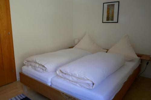 a bed with white sheets and pillows on it at Pension & Ferienwohnungen Haus Edelweiß in Holzgau