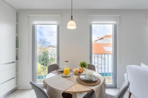 a dining room with a table and chairs and windows at Vilar Charming Studio - Palácio de Cristal in Porto