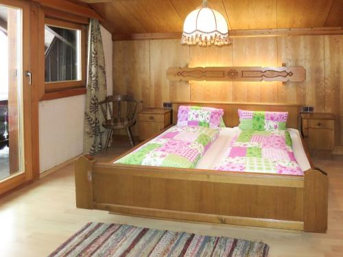 Un dormitorio con una gran cama de madera con almohadas rosas y verdes en Holiday Home Schrofner - MHO538 by Interhome en Ramsau im Zillertal