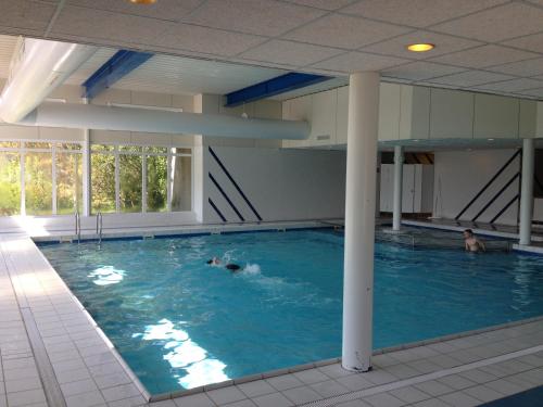 une grande piscine avec 2 personnes dans l'eau dans l'établissement Appartement Kompas, à Hollum