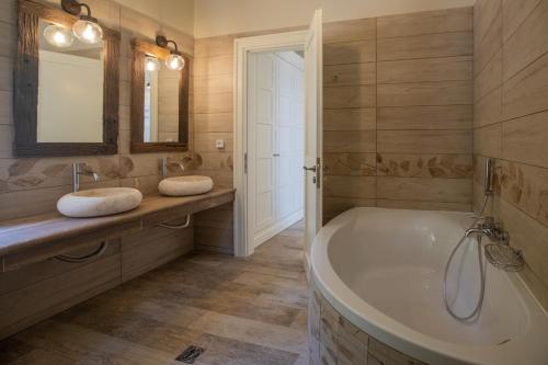 a bathroom with a tub and two sinks and a mirror at Luxury villa above emblisi beach , with heated pool ! in Fiskardho
