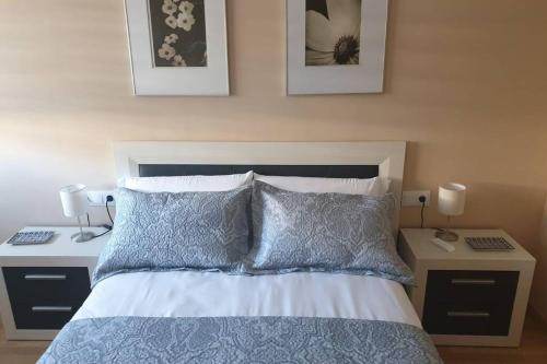 Un dormitorio con una cama con dos mesitas de noche y dos lámparas. en Apartamento para 5 personas frente al mar con piscina y parking, en Cubelles