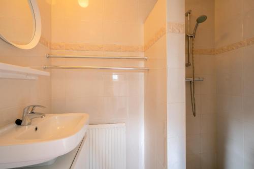 Un baño blanco con lavabo y ducha. en Schapenboet de Boet Waalenburg, en De Koog