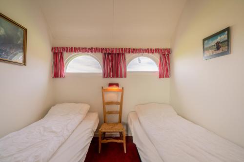 2 camas en una habitación con silla y ventana en Schapenboet de Boet Waalenburg, en De Koog