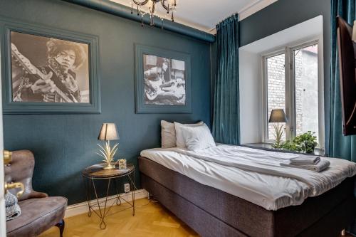 Schlafzimmer mit blauen Wänden, einem Bett und einem Stuhl in der Unterkunft Cameo Boutique Hotell in Ystad