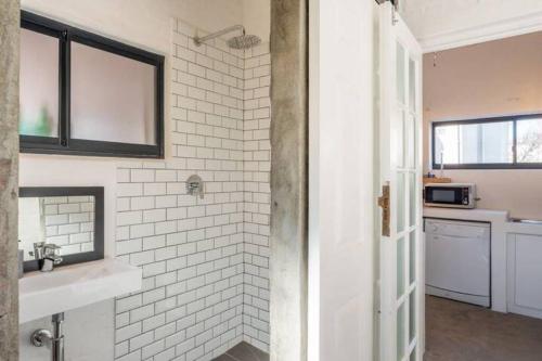 a bathroom with a sink and a white brick wall at Stylish BoKaap Apartment w Mountain Views in Cape Town