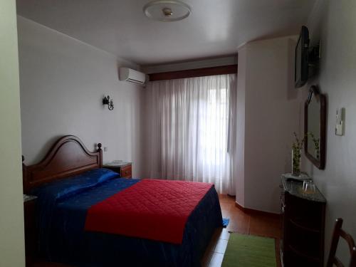 um quarto com uma cama vermelha e azul e uma janela em Residencial das Trinas 2 em Guimarães