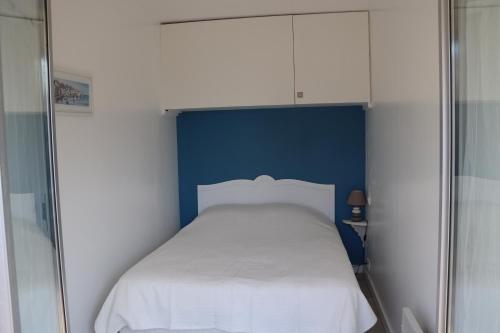 - une petite chambre avec un lit blanc et un mur bleu dans l'établissement RESIDENCE LES BAINS HOULGATE, à Houlgate