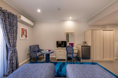 a living room with two chairs a table and a tv at Royal Day Plaza Hotel in 6th Of October