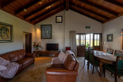 a living room with leather furniture and a dining room at Blue Fattoria Luxury Farm Accomodation in Fernside