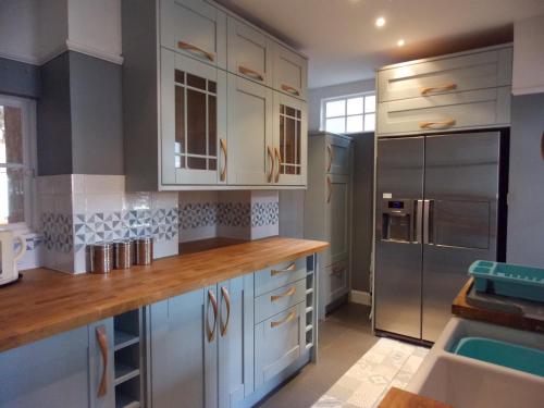 cocina con armarios blancos y nevera de acero inoxidable en Carvetii - Halite House - 3 bed House sleeps up to 5 people, en Tillicoultry