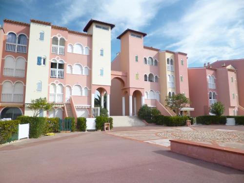 une rangée de bâtiments roses et blancs dans l'établissement Apartment Pointe Vermeille-1 by Interhome, au Barcarès