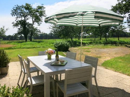 einen weißen Tisch mit einem grünen und weißen Schirm in der Unterkunft Holiday Home Le Petit Maître - LET300 by Interhome in Le Tronchet