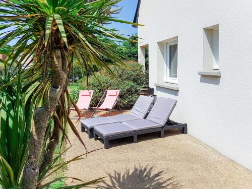 une terrasse avec des chaises longues et un palmier dans l'établissement Holiday Home de la Plage - PBA104 by Interhome, à Pleubian