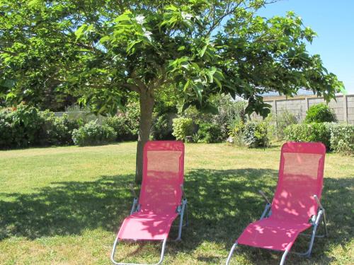 two chairs sitting in the grass under a tree at Holiday Home Les Cordylines - ASM400 in Anneville-sur-Mer
