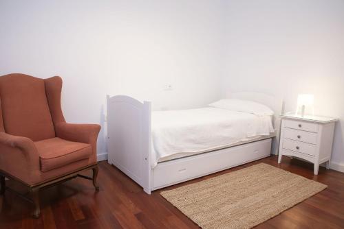 - une chambre avec un lit blanc et une chaise dans l'établissement San Policarpo, à Torrevieja