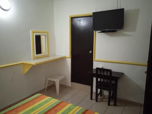 Habitación con escritorio, puerta y silla en Hotel Kiko en Mazatlán