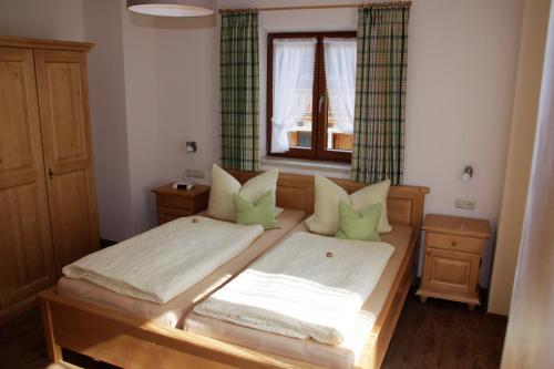 a bedroom with a bed with green pillows and a window at Obergöbllehen in Schönau am Königssee