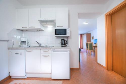 a white kitchen with a sink and a microwave at Garni Rösslhof in Hollersbach im Pinzgau