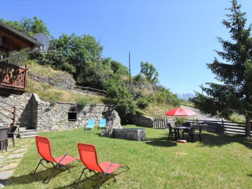 two red chairs and a table in a yard at Apartment Marguerettaz-2 by Interhome in Sarre