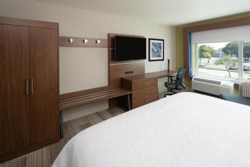 a hotel room with a bed and a desk with a television at Holiday Inn Express Doral Miami by IHG in Doral