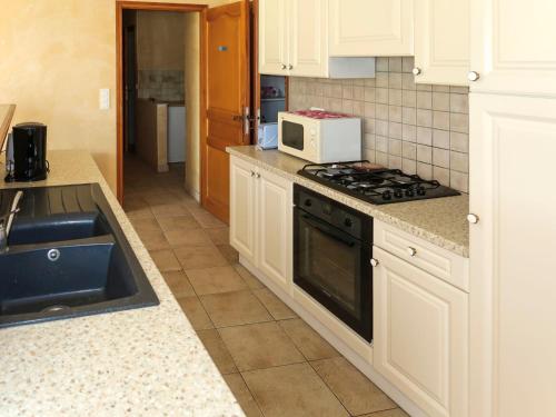 a kitchen with a stove and a microwave at Holiday Home La Cardeline by Interhome in Grillon