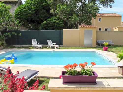 una piscina en un patio con 2 sillas y flores en Villa Kasara - MZN105 by Interhome en Mazan