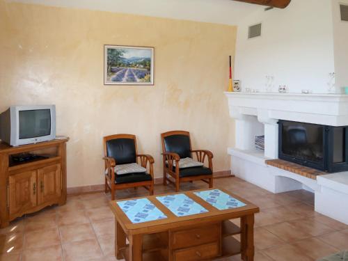 a living room with a fireplace and two chairs and a tv at Holiday Home Plan du Vas by Interhome in Valréas