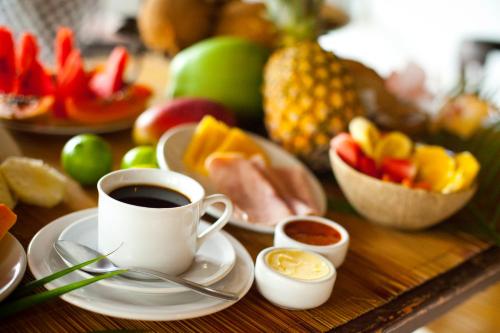 una mesa cubierta con una taza de café y fruta en Pousada Afrika en Búzios