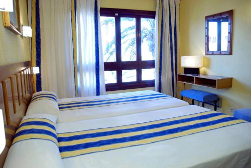 a bedroom with a large bed and a window at Hotel Apartamentos Londres La Manga in La Manga del Mar Menor