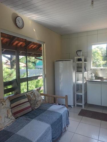 a bedroom with a bed and a kitchen with a refrigerator at Moradas Cantinho da Guarda in Guarda do Embaú