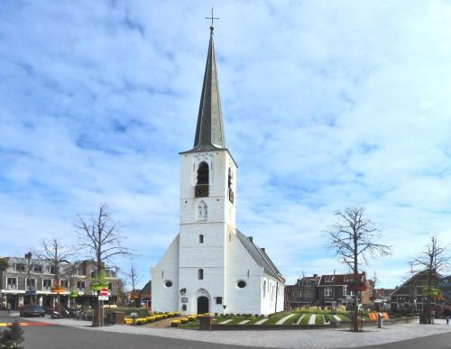 Una iglesia blanca con un campanario con un reloj. en Het Wapen van Noordwijkerhout, en Noordwijkerhout