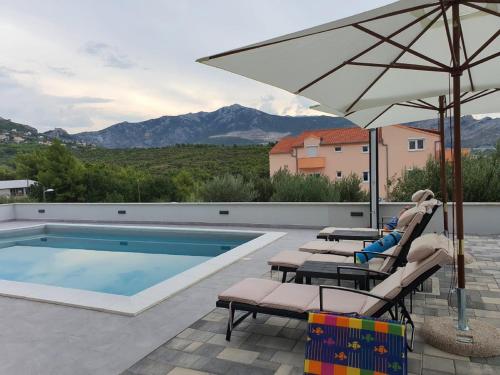 een zwembad met stoelen en een parasol naast een zwembad bij Apartments Villa Salona Sky in Solin