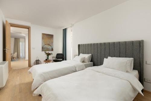 2 bedden in een hotelkamer met witte lakens bij Carsko Selo Blizikuce in Budva