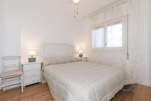 a white bedroom with a bed and a chair at Apartamento Vora Mar 33 in Cambrils