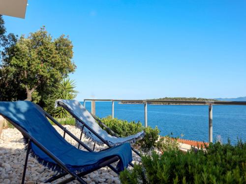 two blue lawn chairs sitting next to the ocean at Apartment Martina - KOR301 by Interhome in Prizba