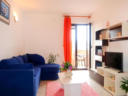a living room with a blue couch and a tv at Apartment Rosić - KRK218 by Interhome in Kornić