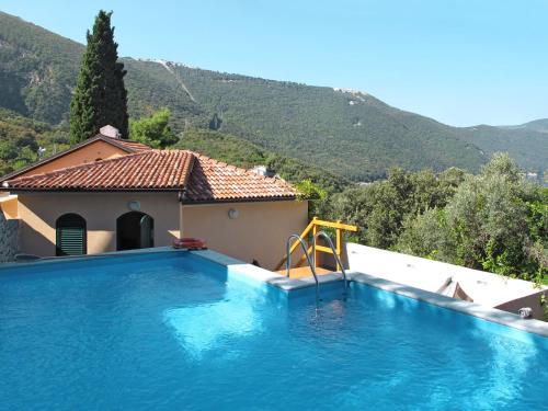 a swimming pool in front of a house with a mountain at Holiday Home Mick - ICS400 by Interhome in Cres