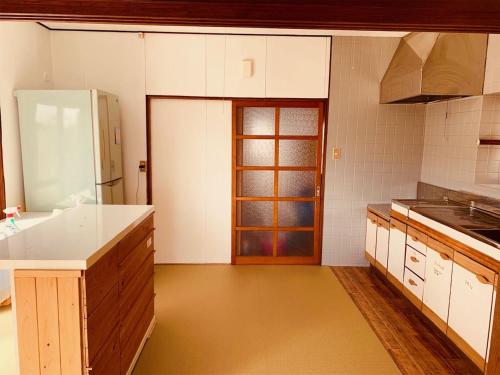 cocina con armarios blancos y puerta de madera en Guest House Nagasaki 1 御船蔵の我が家 1, en Nagasaki