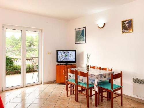 een eetkamer met een tafel en stoelen en een televisie bij Apartment Buda - HVR217 by Interhome in Basina