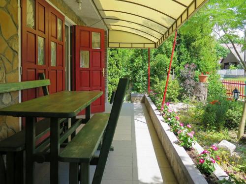 weranda ze stołem, ławkami i czerwonymi drzwiami w obiekcie Holiday Home Rakoczi - MAF139 by Interhome w mieście Balatonmáriafürdő