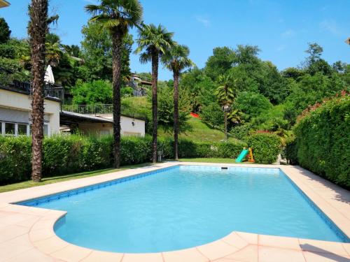 basen z palmami na dziedzińcu w obiekcie Apartment del Sole-3 by Interhome w mieście Luino