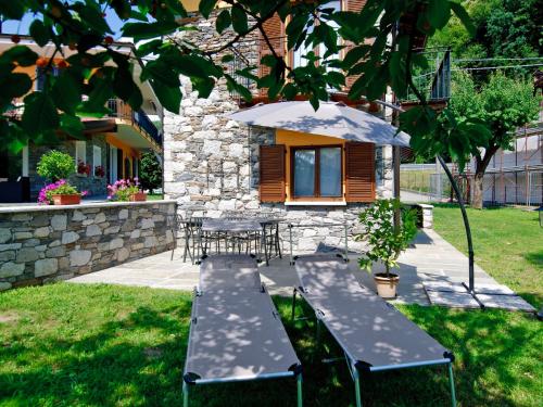 un patio con 2 mesas de picnic y una sombrilla en Holiday Home La Casa di Pipot by Interhome, en Pettenasco