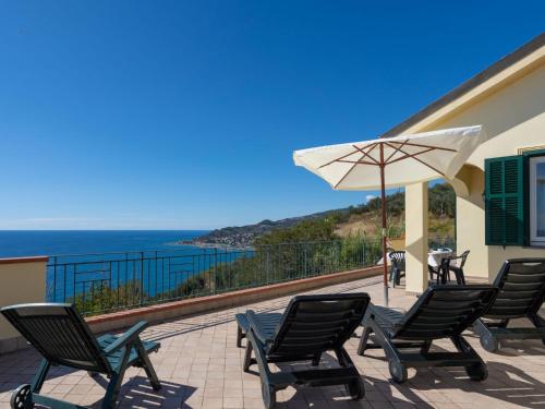 een patio met stoelen en een parasol en de oceaan bij Apartment Primavera - PGI130 by Interhome in Poggi
