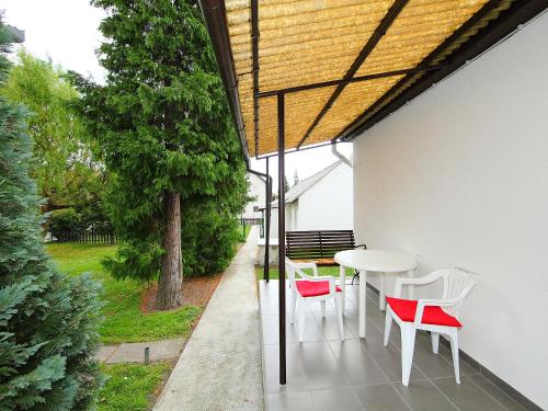 バラトンフェニヴェシュにあるHoliday Home Apricot by Interhomeのパティオ(白いテーブル、赤い椅子付)
