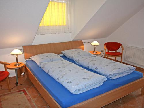 1 Schlafzimmer mit einem Bett mit blauer Bettwäsche und 2 Stühlen in der Unterkunft Apartment Lemke by Interhome in Prerow