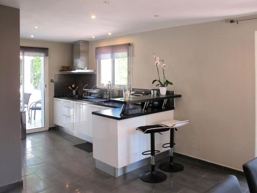une cuisine avec des armoires blanches et un comptoir avec des tabourets dans l'établissement Holiday Home L'Yeuse by Interhome, à Plan Florent
