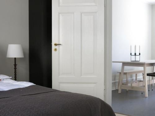 コペンハーゲンにあるApartmentInCopenhagen Apartment 1141の白いドアとテーブル付きのベッドルーム1室